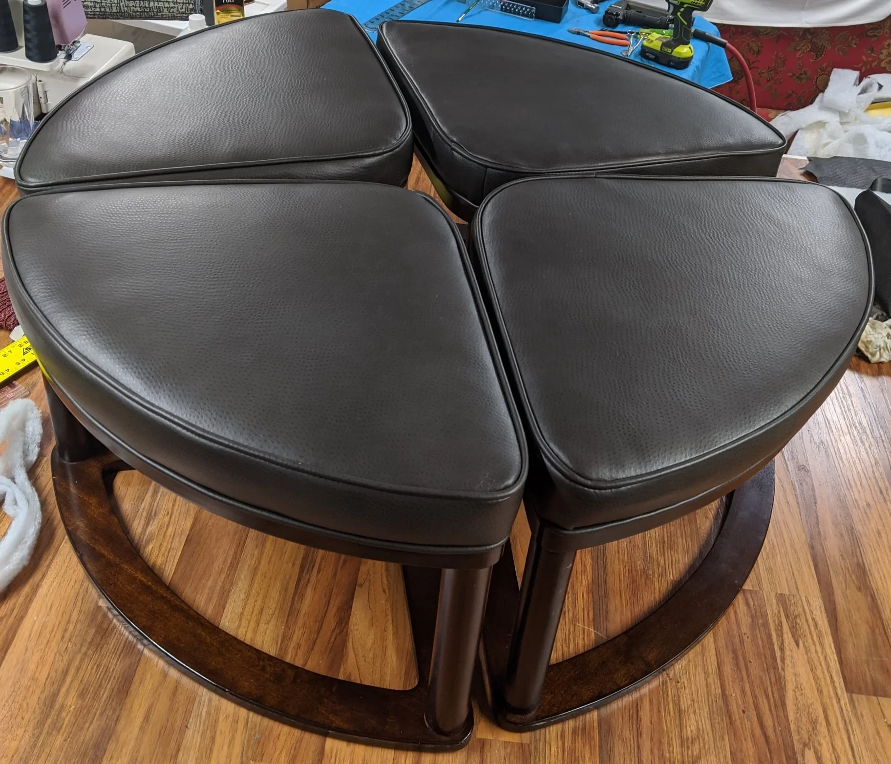 Four matching black upholstered stools arranged in the workshop after renewal.