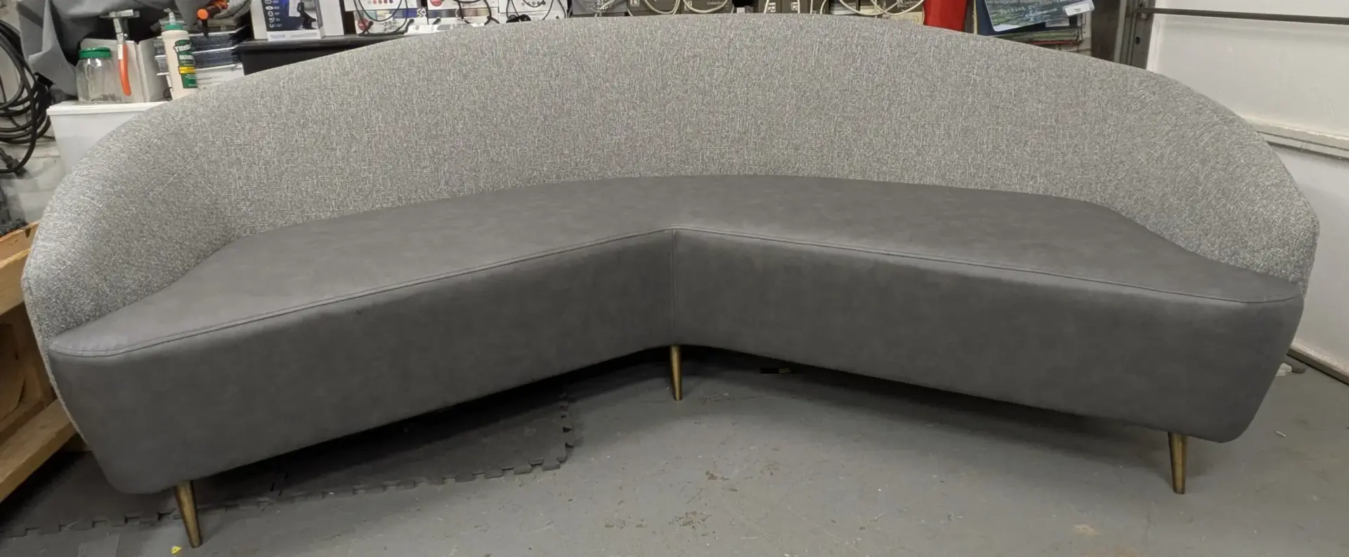 Curved upholstered sofa after reupholstery in gray fabric