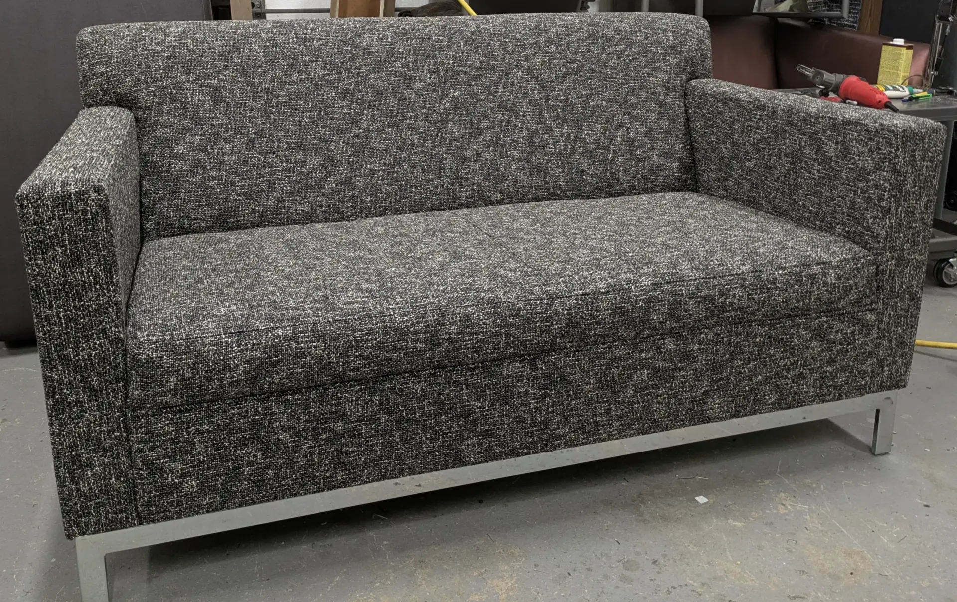 Completed commercial sofa in textured black-and-gray upholstery in the workshop.