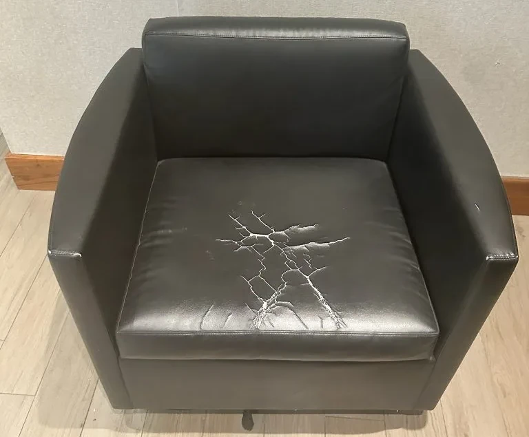 Commercial lounge chair with severely cracked and peeling upholstery before renewal
