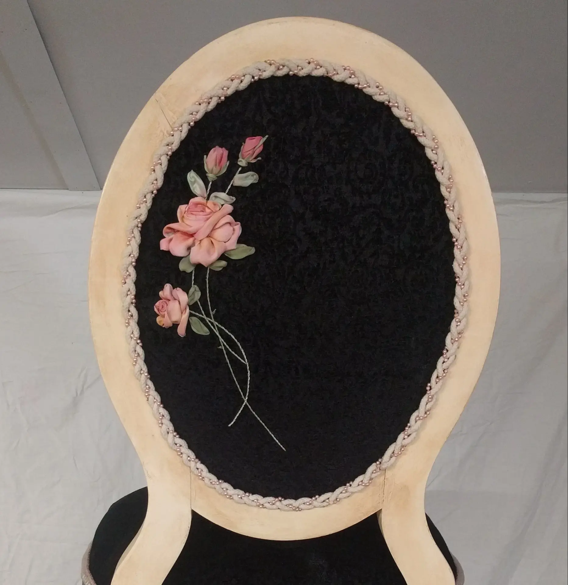 Decorative upholstery detailing with floral embellishment and braided trim on a residential chair